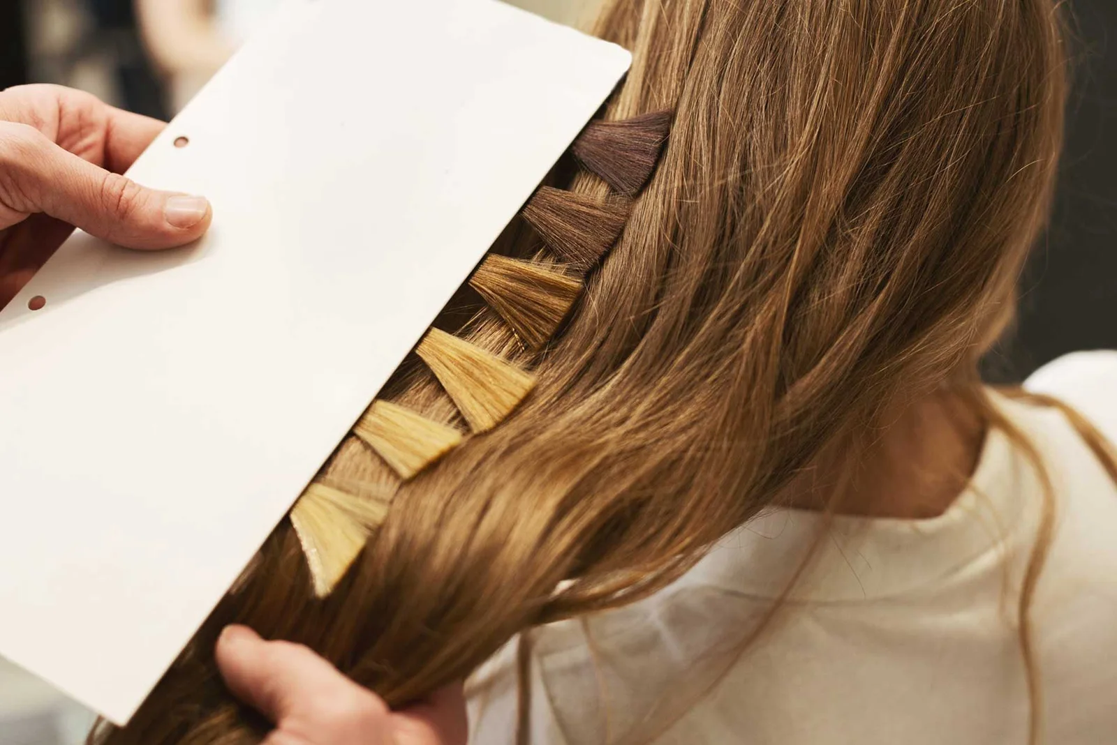Estilista comparando tonos de tinte y coloración para el cabello de una clienta.